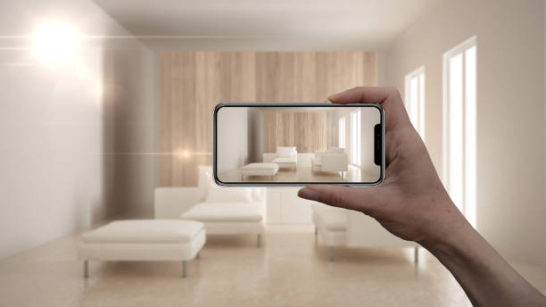 istock Hand holding smart phone, AR application, simulate furniture and interior design products in real home, architect designer concept, blur background, modern living room 1007705040