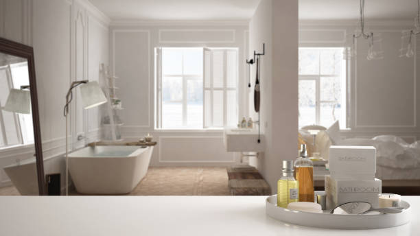 istock Spa, hotel bathroom concept. White table top or shelf with bathing accessories, toiletries, over blurred white scandinavian bathroom, modern architecture interior design 1007705252