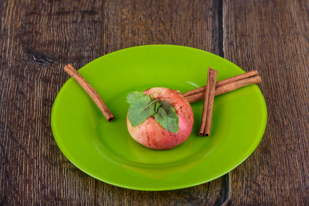 Sliced white apples and cinnamon laid out in a circle on a white background