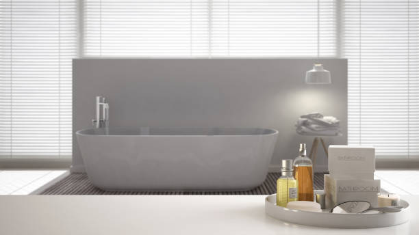 istock Spa, hotel bathroom concept. White table top or shelf with bathing accessories, toiletries, over blurred minimalist bathroom, modern architecture interior design 1007707622