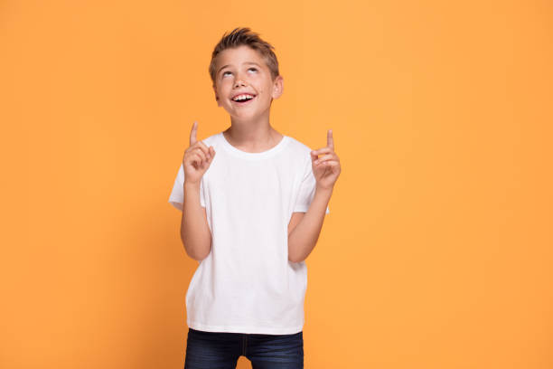 istock Young emotional little boy on orange studio background. 1007707944