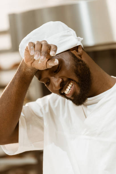 istock tired african american baker wiping sweat on baking manufacture 1007708762