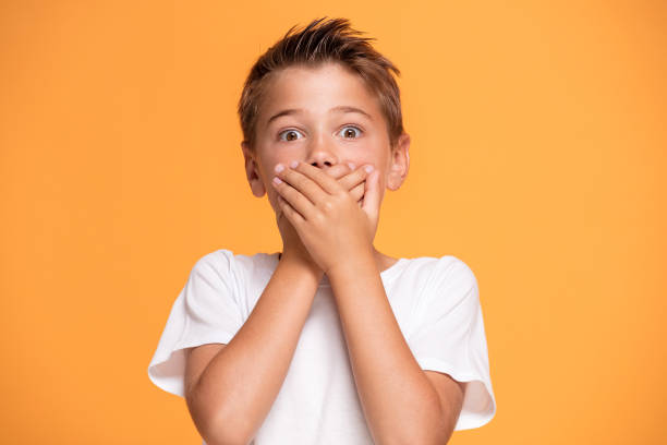 istock Young emotional little boy on orange studio background. 1007709078