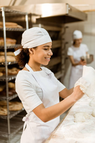 istock female african american baker kneading dough at baking manufacture 1007709812