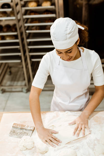 istock high angle view of female baker preparing dough for pastry on baking manufacture 1007711424
