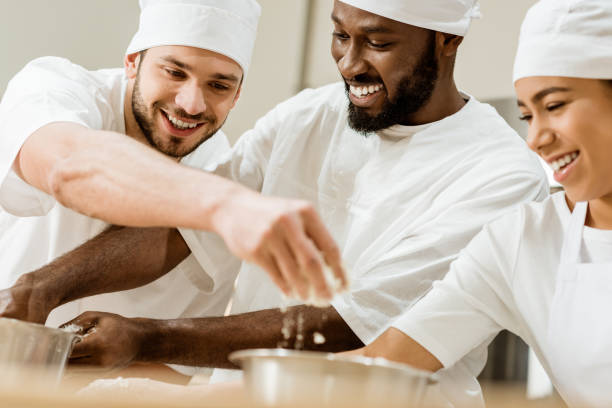 istock laughing group of baking manufacture workers kneading dough together 1007712850