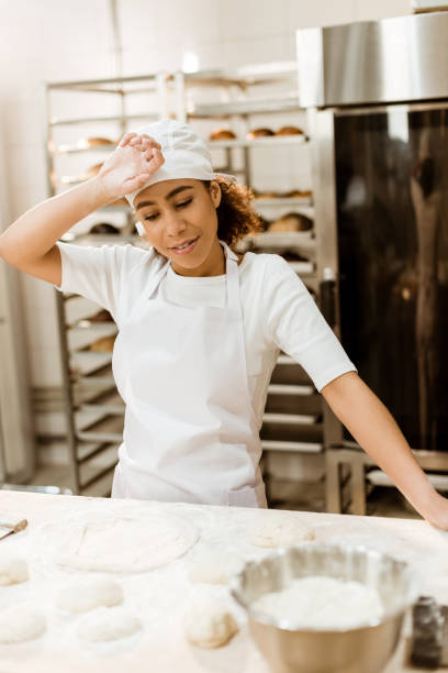 istock overworked female baker wiping sweat from forehead at baking manufacture 1007713012
