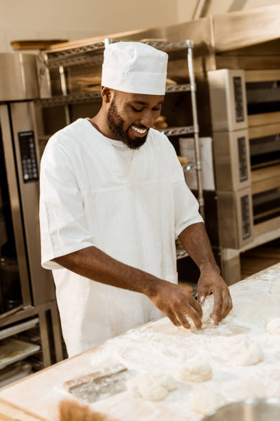 istock smiling african american baker preparing dough on baking manufacture 1007713064