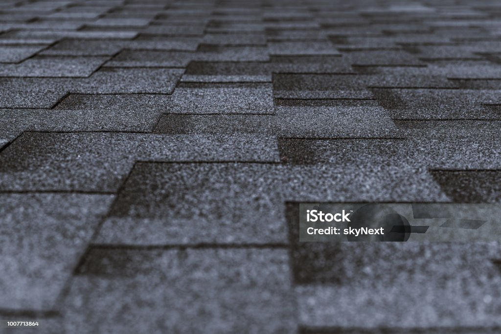 Soft roofing on the top of the building Soft roof tiled gray grainy texture on the top of a village house; grey soft roofing tiles covering a building, focus on the middle distance, shallow depth of field Rooftop Stock Photo