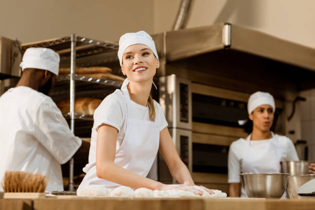 istock young female baker kneading dough at baking manufacture while her colleagues working blurred on background 1007713932