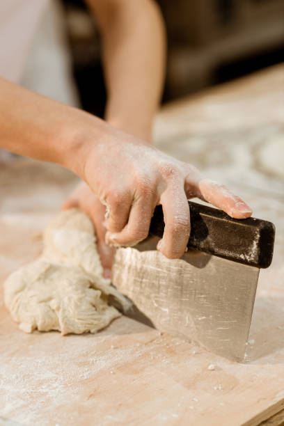 istock cropped shot of baker cutting dough with dough knife 1007716786