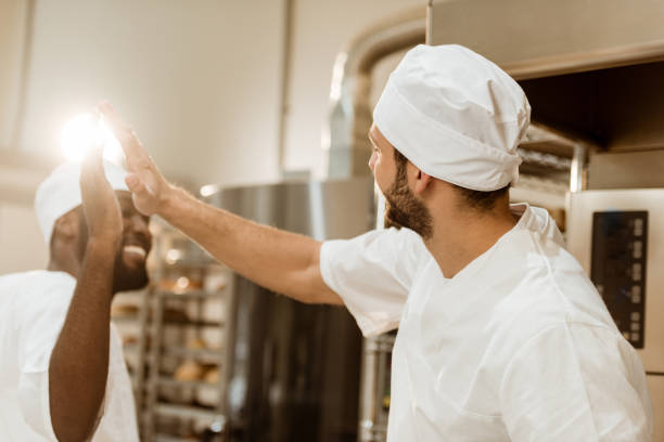 istock handsome young bakers giving high five at baking manufacture 1007716814