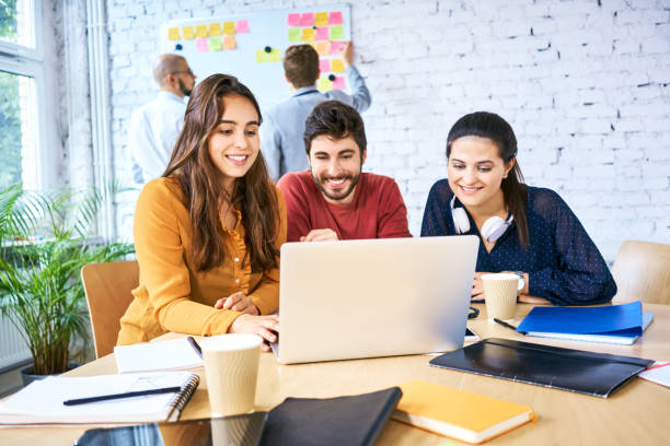 istock Group of young creative workers looking at laptop and brainstorming during meeting. University students studying together 1007727030
