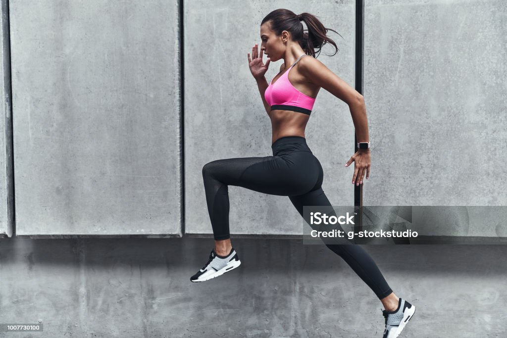 Challenging herself. Modern young woman in sports clothing jumping while exercising outdoors Exercising Stock Photo