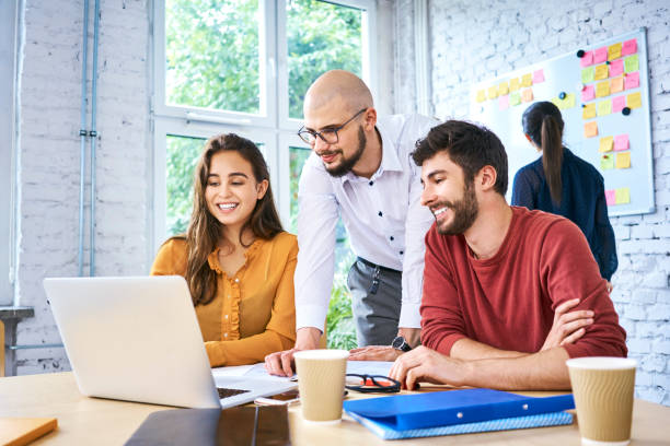 istock Students looking at laptop while studying together in modern classroom. Startup entrepreneurs brainstorming during meeting 1007731296
