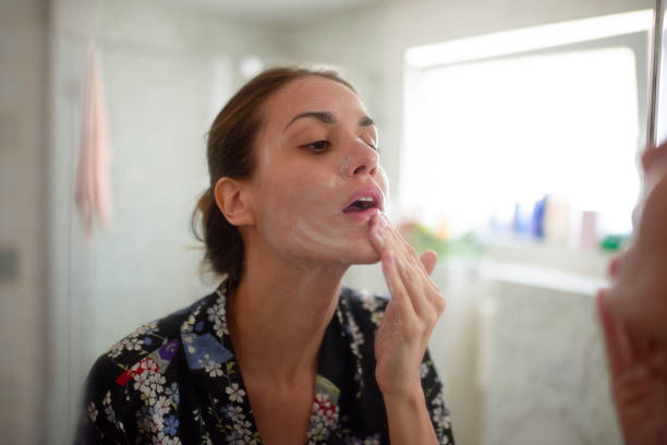 Woman in the bathroom Young female in the bathroom looking in the mirror and taking care of her facial skin. woman washing face stock pictures, royalty-free photos & images