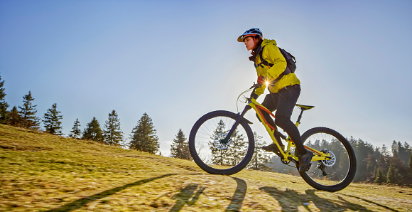 Young female mountain biker riding mountain bike on hill.