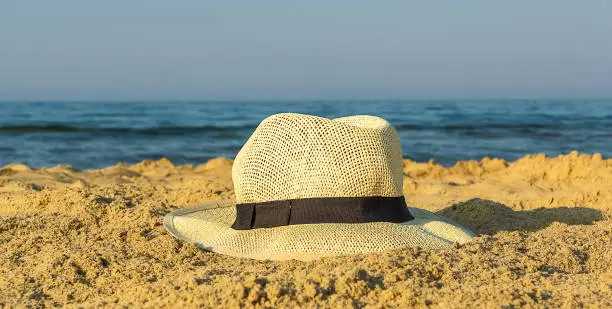 straw hat on sand near the sea, closeup, copy space. Beach and holiday concept.