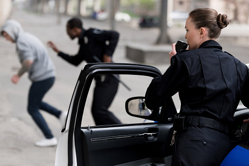 policewoman talking by radio set while her partner chasing thief