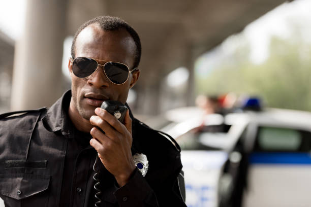 african american police officer talking by walkie-talkie radio set african american police officer talking by walkie-talkie radio set walkie talkie photos stock pictures, royalty-free photos & images