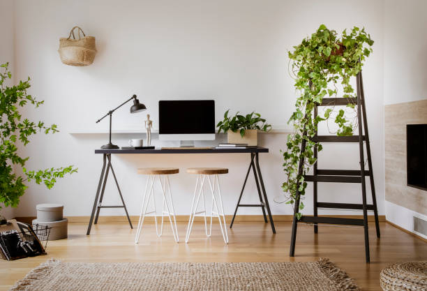 istock Lamp and computer desktop on black desk in workspace interior with stools and plants. Real photo 1007756460