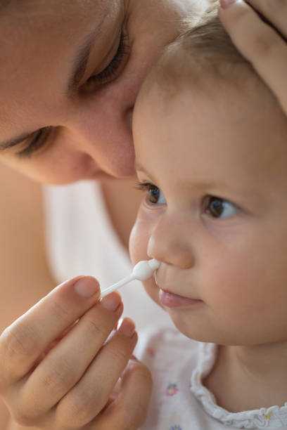 istock mother cleaning babies nose with cotton swabs 1007763264