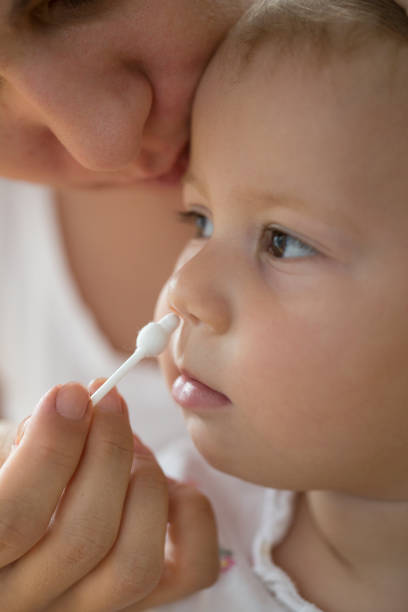 istock mother cleaning babies nose with cotton swabs 1007763296