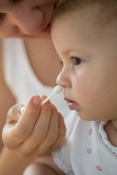 istock mother cleaning babies nose with cotton swabs 1007763316