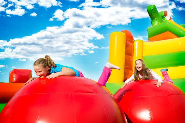 Girls Jupming Fun Happy little girls having lots of fun while jumping from ball to ball on an inflate castle. bouncing photos stock pictures, royalty-free photos & images