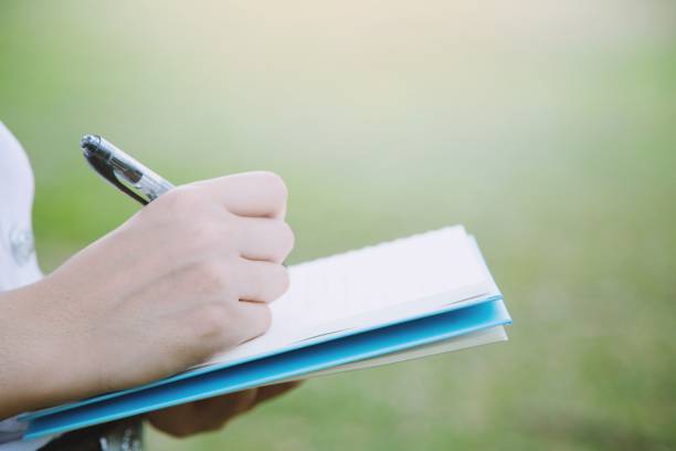 istock young woman holding notebook with pen and writing on the park 1007769778