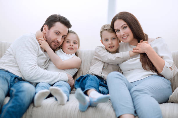 istock parents hug their children sitting on the couch 1007776320