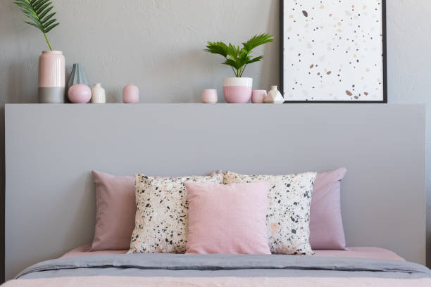 istock Pink and patterned pillows on bed with headboard in grey bedroom interior with poster. Real photo 1007776620