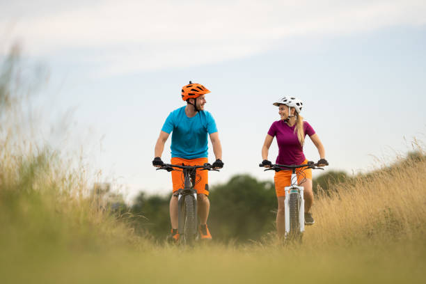 istock low angle view happy couple cycling in grassland smiling at each other 1007781992