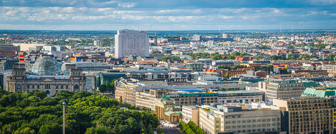 Aerial panoramic vista over the green foliage of the Tiergarten to the iconic facade and glass dome of the Reichstag, the Brandenburg Gate and Unter den Linden in the the heart of Berlin, Germany’s vibrant capital city.