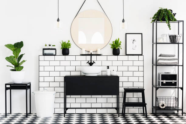 istock Mirror between plants above black washbasin in bathroom interior with checkered floor. Real photo 1007787534