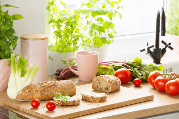istock Baguette, tomatoes, pink mug, celery and herbs on a countertop in a kitchen interior. Real photo 1007790986