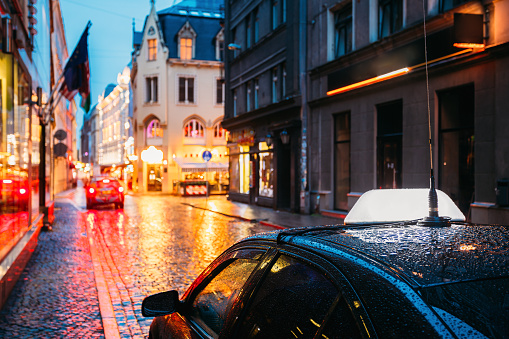 Taxi Car Wait Clients Near Cafe In Old European Streets In Rainy Evening. Night Street Illuminations.