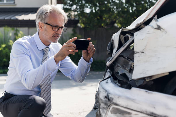 Insurance expert at work Insurance expert examining crushed car after accident car accident photos stock pictures, royalty-free photos & images