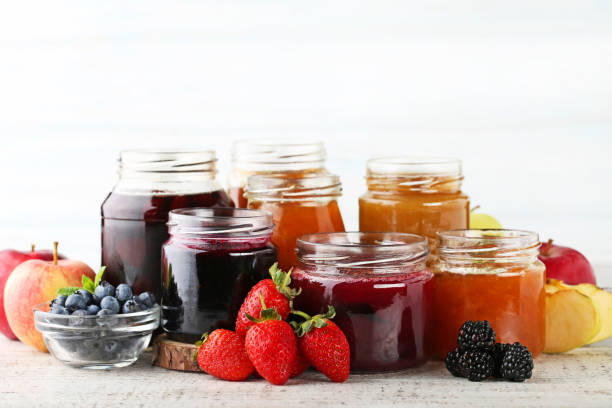 istock Glass jars with different kinds of jam on wooden table 1007797770