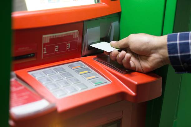 istock Hand inserting ATM card into bank machine to withdraw money 1007807162