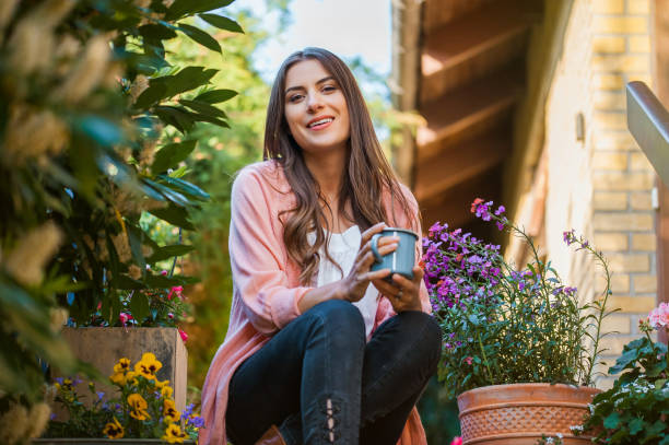 bella ragazza sulla terrazza di casa, bevendo una bevanda calda. - balcony women patio coffee foto e immagini stock