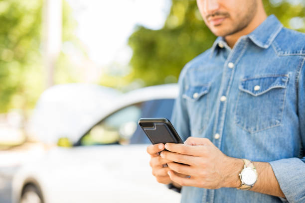 Man calling roadside assistance Close up of man hands using phone with broken car in background. Man calling roadside assistance for his breakdown car stranded stock pictures, royalty-free photos & images
