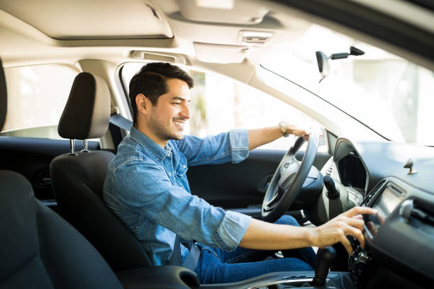 Man switching radio station while driving Handsome young man in denim shirt pressing touchscreen on car multimedia panel, switching shifting radio station. happy people audio stock pictures, royalty-free photos & images