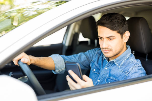 Reckless man driving car and using phone Portrait of reckless male driver using his mobile phone behind the wheel Distracted stock pictures, royalty-free photos & images