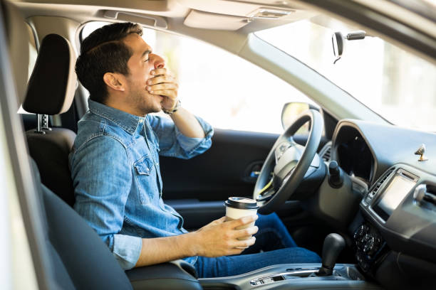 Tired man driving back to home Young man feeling tired and yawning while driving a car tired stock pictures, royalty-free photos & images