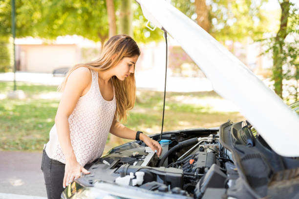 istock Woman looking at the engine of her broken car 1007814902