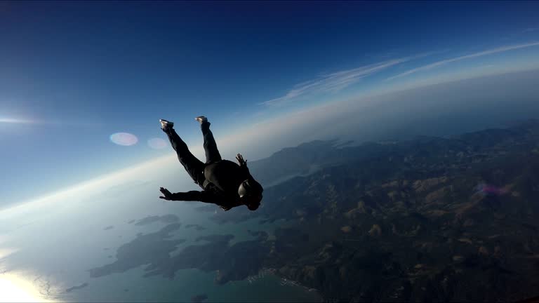 Skydiver having fun above the sea & mountains 4K