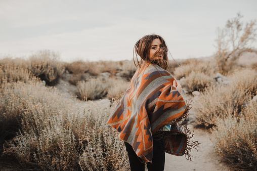 Boho woman with windy hair. Hipster girl in gypsy look, young traveler in the desert nature.