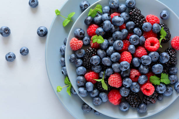 fruit salad with blackberry, blueberry, raspberry and mint leaves on wooden gray background. flat lay. top view - fruta com grão imagens e fotografias de stock