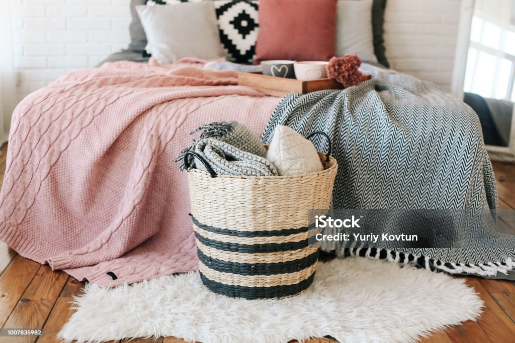 bedroom interior basket with blankets stands bedroom in the interior, a basket with blankets stands near the bed on a carpet of fur Blanket Stock Photo